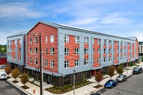 Portland apartment for rent - A red and grey building with a parking lot in front.