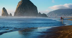 Seaside apartment for rent - A beach scene with people and large rock formations.