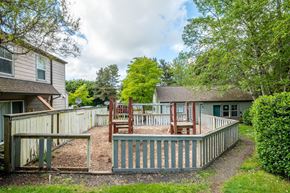 Cannon Beach apartment for rent - a backyard with a deck and a play yard with chairs