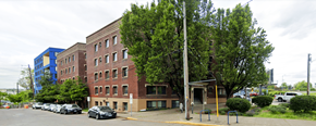 Portland apartment for rent - A parking lot with cars and a building in the background.