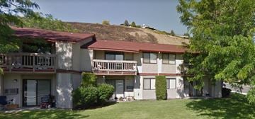 Selah apartment for rent - an apartment building with a grass covered hill in the background
