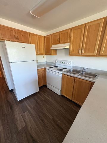 Portland apartment for rent - A white refrigerator stands in a kitchen with wooden cabinets.