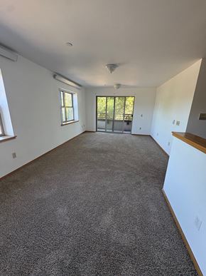 Portland apartment for rent - A large empty room with a carpeted floor and a window.