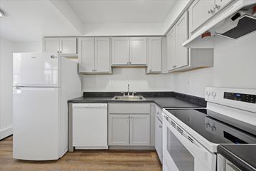 East Windsor apartment for rent - A white refrigerator stands in a kitchen with white cabinets and black countertops.