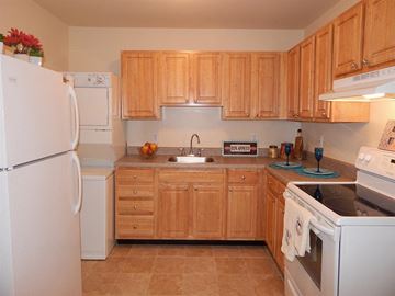 Mercerville apartment for rent - a kitchen with white appliances and wooden cabinets