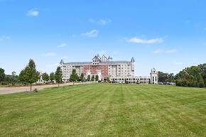 Grandville apartment for rent - A large white building with a red roof is surrounded by a green lawn.