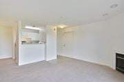 Ashburn apartment for rent - A white room with a fireplace and a kitchen area in the background.