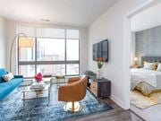 Arlington apartment for rent - A modern living room with a blue couch, a wooden chair, and a large window.