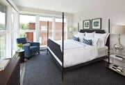 Arlington apartment for rent - A bedroom with a large bed and a blue chair by the window.