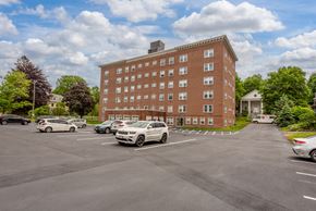 Portsmouth apartment for rent - A parking lot with cars and a red brick building in the background.