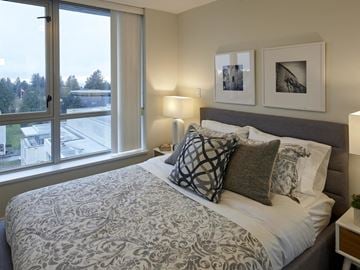 Vancouver apartment for rent - A bedroom with a large bed and a window overlooking a parking lot.