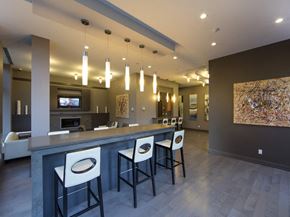 Etobicoke apartment for rent - a bar with white chairs and a gray countertop in front of a living room with a