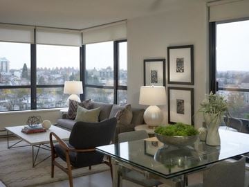 Vancouver apartment for rent - A modern living room with a glass table and a view of the city.