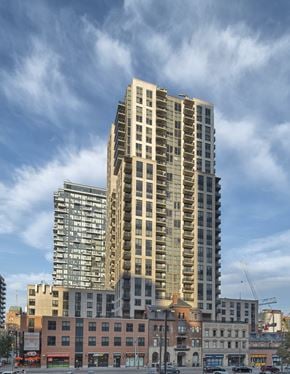 Toronto apartment for rent - A tall building with many windows stands in front of a sky with clouds.
