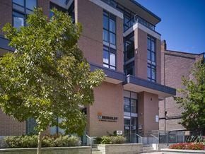 Toronto apartment for rent - A modern building with a glass entrance and a tree in front.