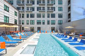 Richmond apartment for rent - A long rectangular pool with blue and white loungers on either side.