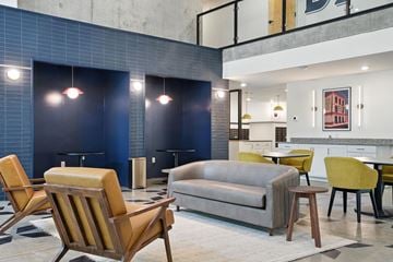 Richmond apartment for rent - A modern living room with a grey couch, yellow chairs and a blue tiled wall.