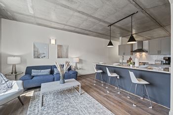 A living area with a sofa coffee table and a kitchen with a breakfast bar