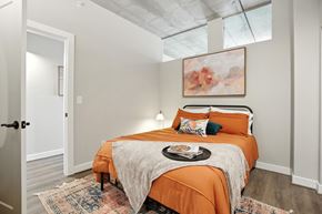 Richmond apartment for rent - A bedroom with a bed covered in an orange bedspread and a painting above it.
