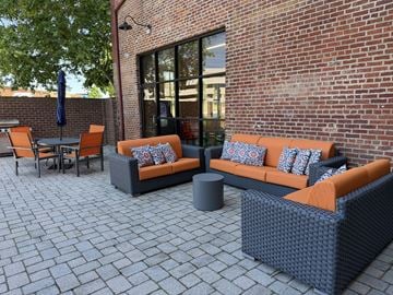 Richmond apartment for rent - A patio with a black wicker couch and orange cushions.