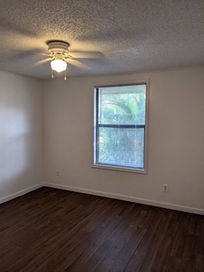 Cocoa apartment for rent - an empty living room with a ceiling fan and a window