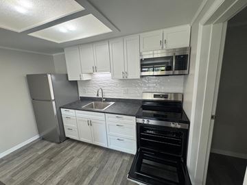 Titusville apartment for rent - A kitchen with white cabinets and a black stove top oven.