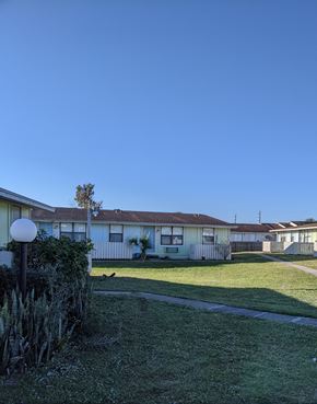 Cocoa apartment for rent - a row of houses with a yard and a blue sky