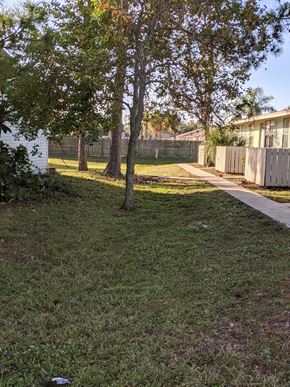 Cocoa apartment for rent - a yard with a fence and trees and a sidewalk
