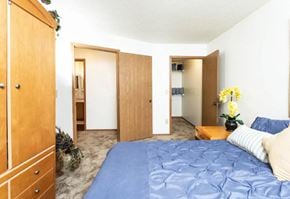 Delaware apartment for rent - A bedroom with a blue bedspread and a wooden wardrobe.