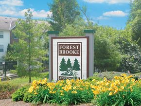 Delaware apartment for rent - A sign for Forest Brooke Apartments is surrounded by yellow flowers.