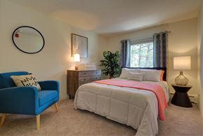 Seabrook apartment for rent - A bedroom with a bed, a blue chair, and a plant.