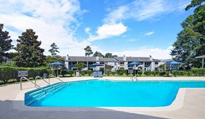 Summerville apartment for rent - A swimming pool surrounded by trees and a building in the background.
