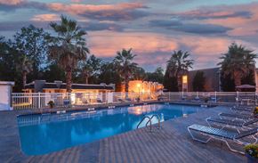 Summerville townhouse for rent - A pool surrounded by palm trees and lounge chairs.