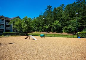 Durham apartment for rent - A playground with a seesaw and a slide in the middle of a sandy area.