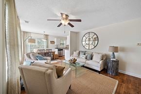Bluffton apartment for rent - A living room with a beige couch, a glass coffee table, and a ceiling fan.