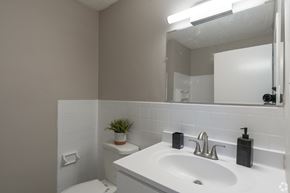 Glassboro apartment for rent - A white bathroom with a toilet, sink, and mirror.