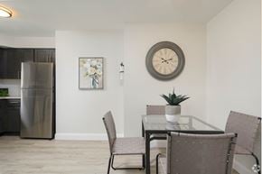 Glenolden apartment for rent - A modern kitchen with a glass table and chairs, a fridge, and a clock on the wall.