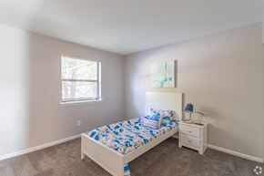 Newark apartment for rent - A bedroom with a bed, nightstand, and window.