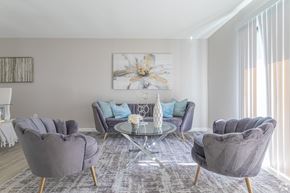 Newark apartment for rent - A living room with grey chairs and a glass table.