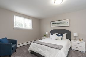 Pottstown apartment for rent - A bedroom with a large bed, a blue chair, and a painting on the wall.