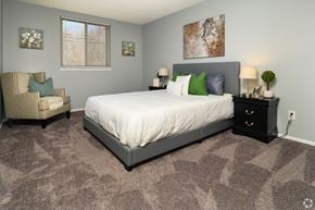 Newark apartment for rent - A bedroom with a large bed, a chair, and a painting on the wall.