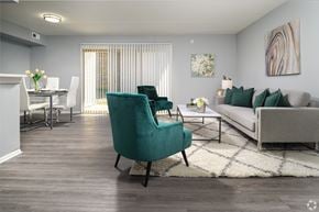 Newark apartment for rent - A living room with a green chair in the foreground and a dining area in the background.