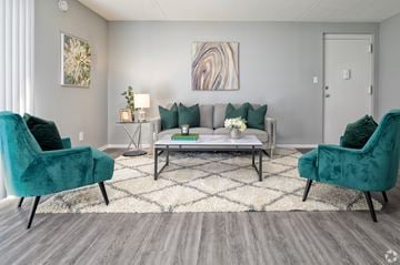 Newark apartment for rent - A living room with a grey couch, two green chairs and a coffee table.