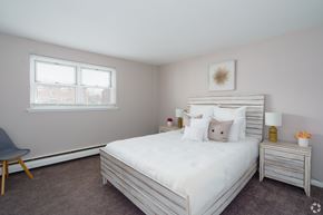 Bensalem apartment for rent - A bedroom with a large bed, a chair, and a nightstand with a lamp.