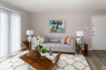 Newark apartment for rent - A modern living room with a grey couch, a wooden coffee table, and a painting on the wall.