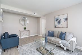 Allentown apartment for rent - A living room with a grey couch, a blue armchair, and a glass coffee table.