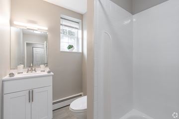 Barrington apartment for rent - A white bathroom with a toilet, sink, and mirror.