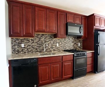 Philadelphia apartment for rent - A kitchen with dark wood cabinets and black appliances.