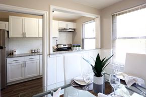 Collingswood apartment for rent - A kitchen with white cabinets and a dining table set for two.