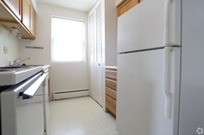 Pottstown apartment for rent - A white refrigerator stands in a kitchen with wooden cabinets and a stainless steel dishwasher.